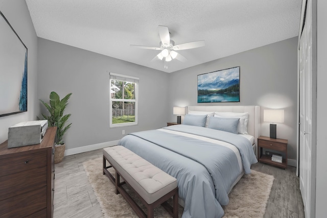 bedroom featuring ceiling fan, a textured ceiling, and light wood-type flooring