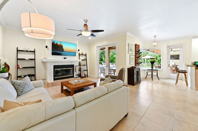 tiled living room with ceiling fan with notable chandelier and ornamental molding