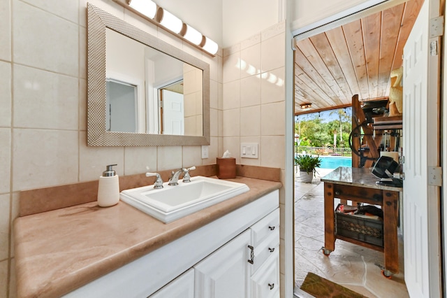 bathroom with vanity, wooden ceiling, and tile walls