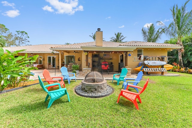 rear view of property featuring a patio, a fire pit, ceiling fan, and a lawn