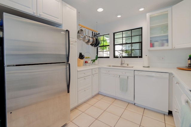 kitchen with white cabinets, sink, white dishwasher, and stainless steel refrigerator