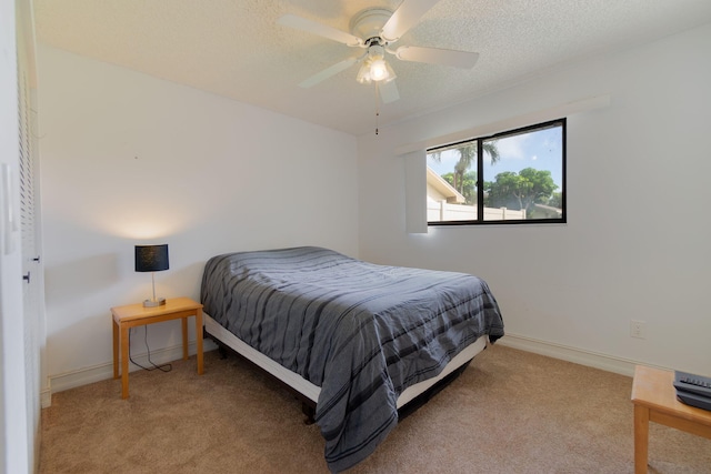 carpeted bedroom with ceiling fan and a textured ceiling