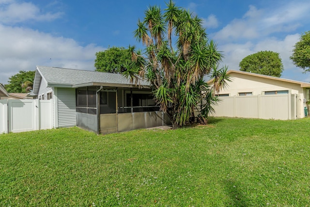 rear view of house with a sunroom and a yard