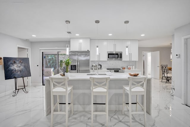 kitchen with a breakfast bar, white cabinetry, hanging light fixtures, and stainless steel appliances