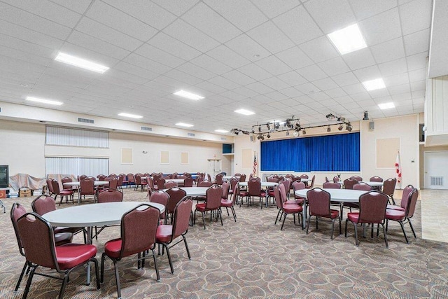 dining area with rail lighting and a drop ceiling