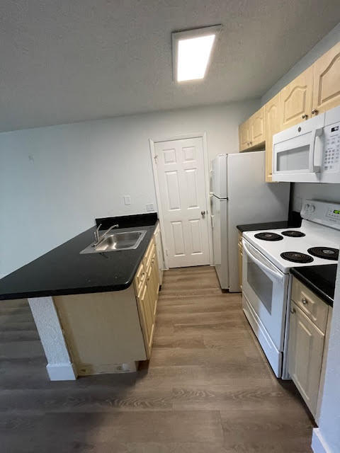 kitchen featuring white appliances, dark hardwood / wood-style flooring, and sink