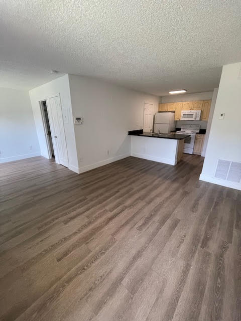 unfurnished living room with dark wood-type flooring and a textured ceiling