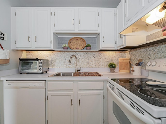 kitchen with white appliances, under cabinet range hood, white cabinetry, and a sink