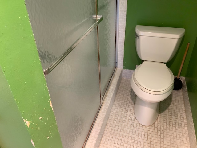 bathroom with an enclosed shower, tile patterned flooring, and toilet