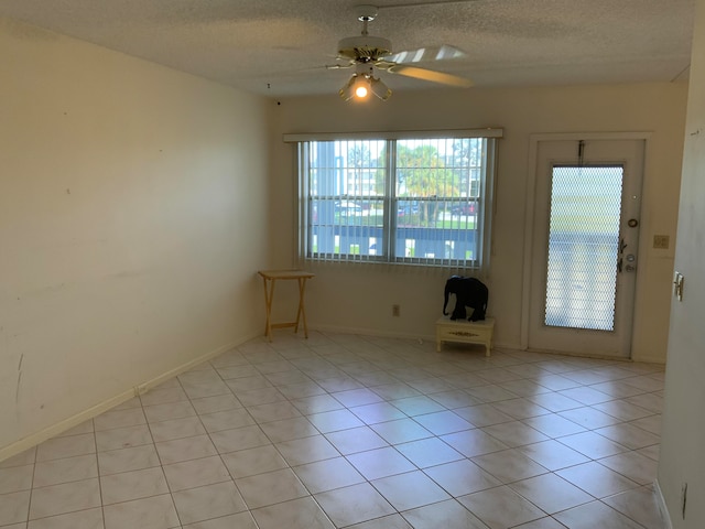 spare room with ceiling fan, light tile patterned floors, and a textured ceiling