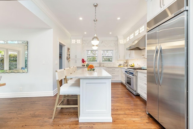 kitchen with pendant lighting, white cabinetry, high end appliances, and plenty of natural light