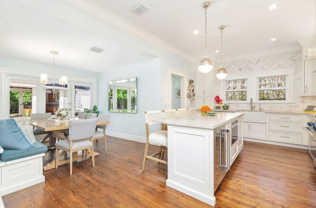 kitchen with white cabinetry, hardwood / wood-style flooring, a center island, and hanging light fixtures