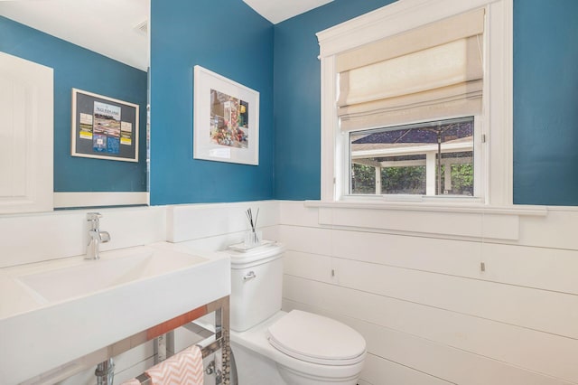 bathroom with toilet, tile walls, and sink