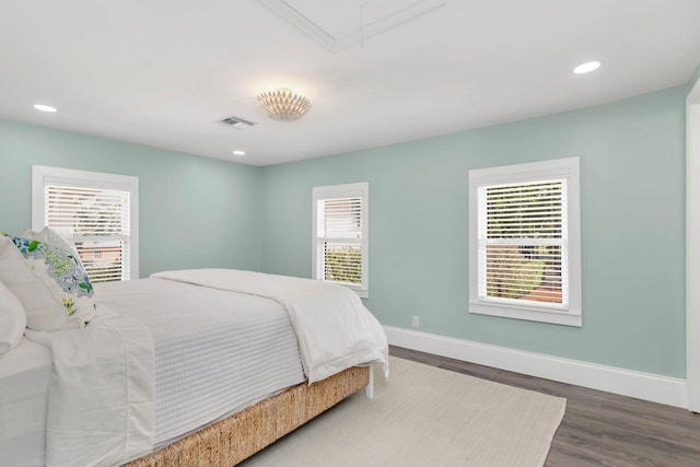 bedroom with multiple windows and dark hardwood / wood-style floors