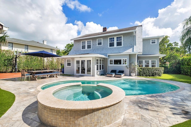 rear view of property with a patio, french doors, and a swimming pool with hot tub