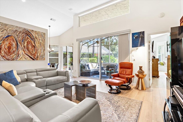 living room featuring a notable chandelier, high vaulted ceiling, and light hardwood / wood-style floors