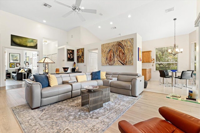 living room featuring light hardwood / wood-style flooring, ceiling fan with notable chandelier, and high vaulted ceiling