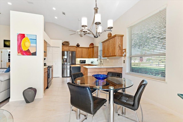 tiled dining room featuring sink, vaulted ceiling, and ceiling fan with notable chandelier