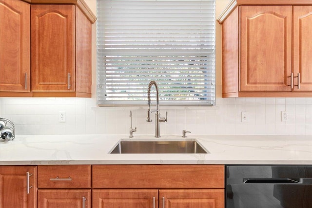 kitchen featuring decorative backsplash, dishwasher, light stone countertops, and sink