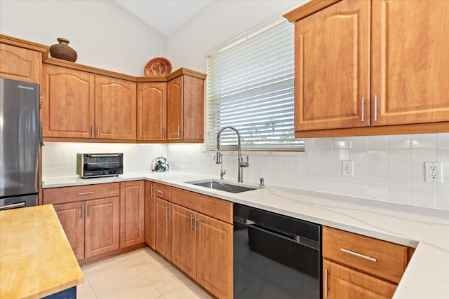 kitchen featuring decorative backsplash, stainless steel refrigerator, dishwasher, light tile patterned flooring, and sink