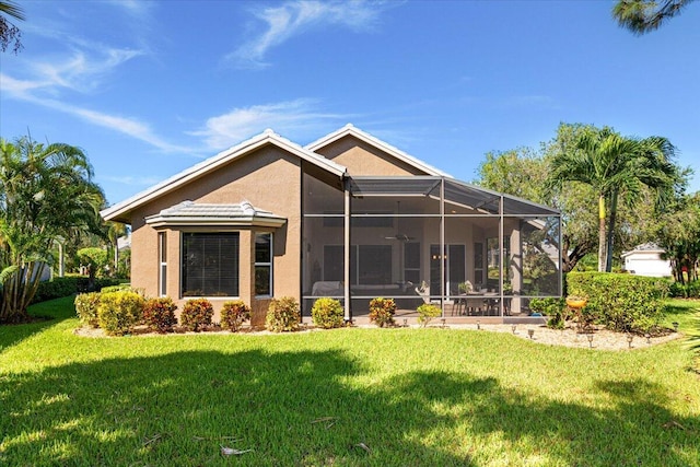 rear view of property featuring a yard and glass enclosure