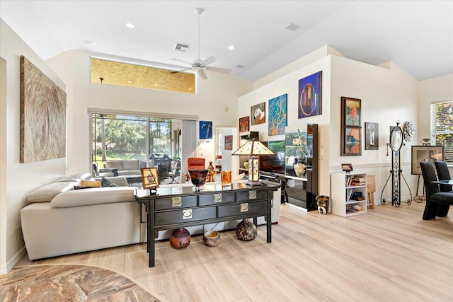 living room with light hardwood / wood-style floors, high vaulted ceiling, and ceiling fan