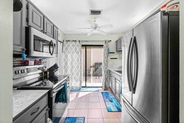 kitchen featuring gray cabinets, stainless steel appliances, light tile patterned floors, and ceiling fan