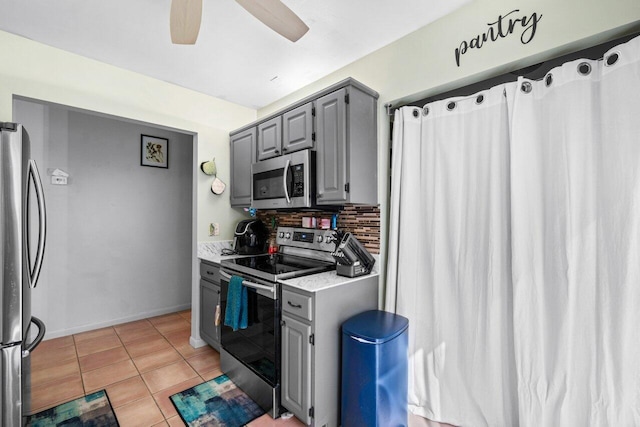 kitchen with gray cabinetry, ceiling fan, appliances with stainless steel finishes, and light tile patterned floors