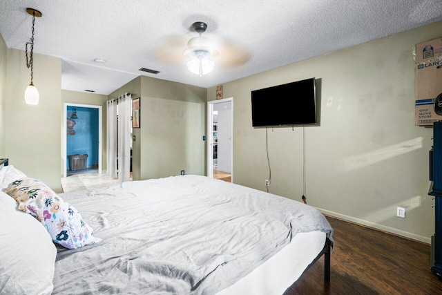 bedroom with connected bathroom, ceiling fan, a textured ceiling, and dark hardwood / wood-style floors