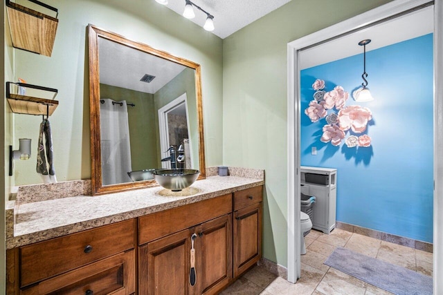 bathroom with vanity, a textured ceiling, and toilet