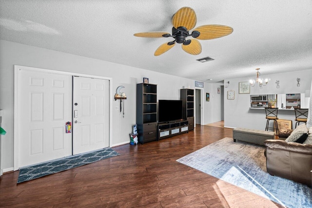 living room with a textured ceiling, ceiling fan with notable chandelier, and dark hardwood / wood-style flooring