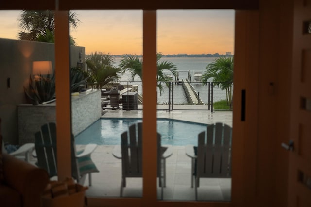 pool at dusk featuring a water view