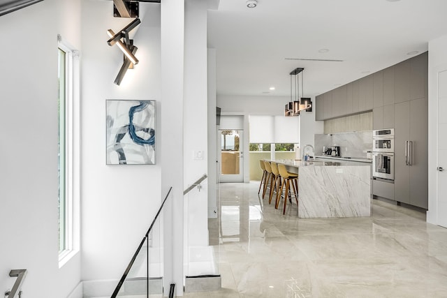 kitchen featuring pendant lighting, gray cabinets, stainless steel double oven, and plenty of natural light