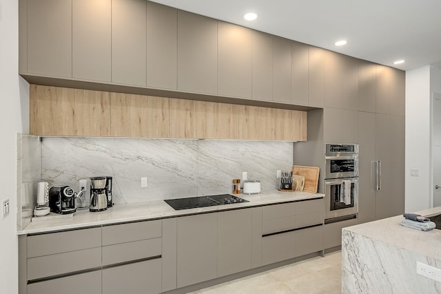 kitchen with stainless steel double oven, backsplash, gray cabinetry, and black electric stovetop