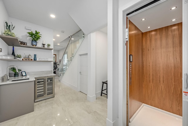 bar featuring elevator, sink, and wine cooler