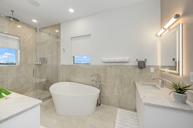 bathroom with separate shower and tub, vanity, and tile walls