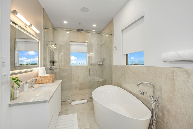 bathroom with tile patterned flooring, plus walk in shower, vanity, and tile walls