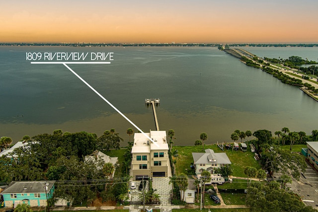 aerial view at dusk featuring a water view