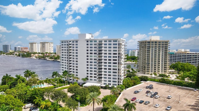 view of building exterior with uncovered parking, a view of city, and a water view