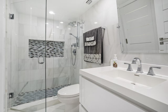 bathroom featuring vanity, tile walls, visible vents, toilet, and a shower stall