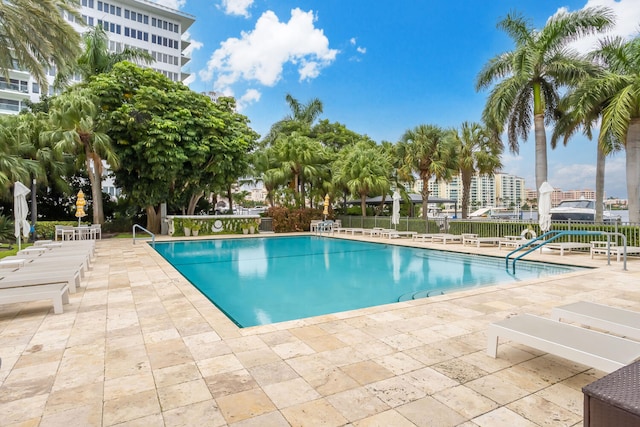 community pool with fence, a patio area, and a view of city