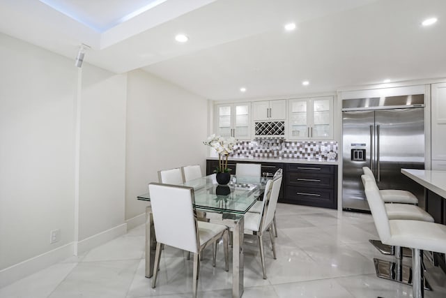 dining space featuring baseboards, recessed lighting, and a bar