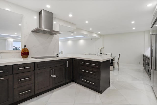 kitchen featuring wall chimney range hood, light countertops, a peninsula, and black electric stovetop