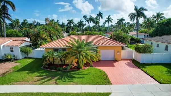 mediterranean / spanish-style house featuring a front yard and a garage