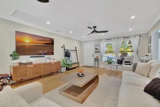 living room featuring light hardwood / wood-style floors, crown molding, and ceiling fan