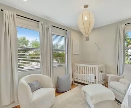 bedroom featuring a nursery area, wood-type flooring, and radiator