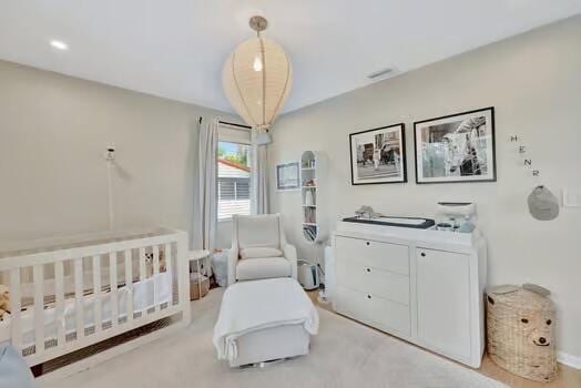 bedroom with light colored carpet and a crib