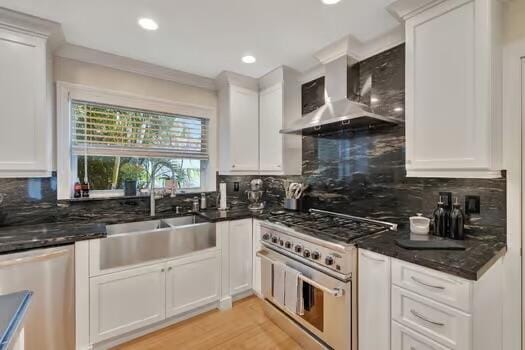 kitchen featuring wall chimney exhaust hood, stainless steel appliances, decorative backsplash, and white cabinets