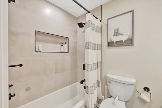 bathroom featuring shower / bath combination with curtain and toilet