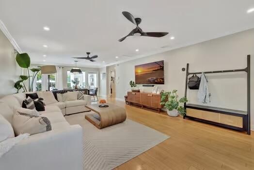 living room featuring ornamental molding, light hardwood / wood-style flooring, and ceiling fan